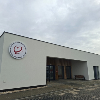 Nowoczesny, parterowy budynek Regionalnego Centrum Krwiodawstwa i Krwiolecznictwa z jasną elewacją. Na ścianie widoczne okrągłe logo RCKiK w Katowicach.